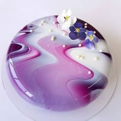 a cake with purple and white frosting on the top, decorated with pansies