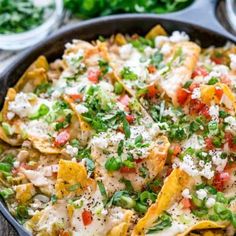 a skillet filled with nachos topped with cheese and veggies