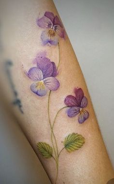 a close up of a person's leg with tattoos on it and purple flowers