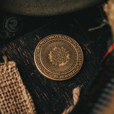 a gold coin sitting on top of a piece of cloth next to a black hat