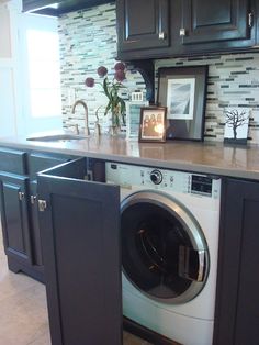 a washer and dryer sitting in a kitchen next to a counter with flowers on it