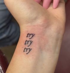 a woman's wrist tattoo with the words try try and try written on it