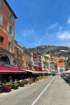 an empty street lined with colorful buildings and people sitting at tables in front of them