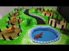 a cake that has animals on it and is shaped like a pond with water in the middle