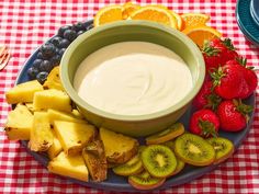 a bowl of dip surrounded by fruit on a plate