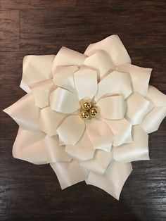 a large white flower with gold centers on a wooden surface in front of a wood floor