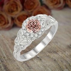 a pink diamond engagement ring on top of a wooden table with roses in the background