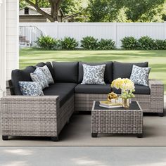 an outdoor living room with grey wicker furniture and blue pillows on the couches