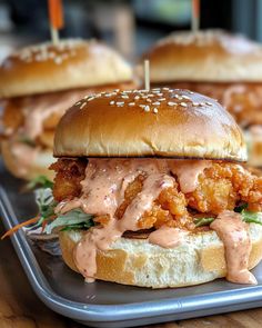 two chicken burgers on a tray with toothpicks sticking out of them