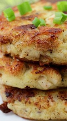 three crab cakes stacked on top of each other with scallions and green onions