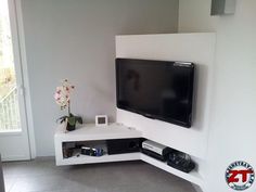 a flat screen tv mounted to the side of a white wall in a living room