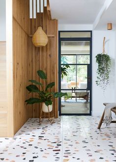 a living room with wood paneling and plants on the wall next to an open door