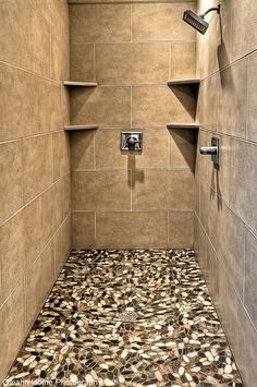 a walk in shower sitting next to a tiled wall and floor with shelves on each side