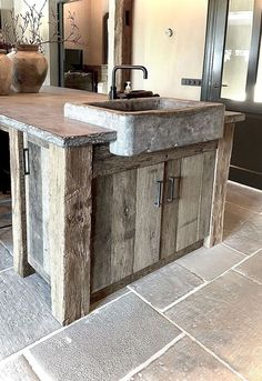 a kitchen island made out of wood and concrete with a sink in the center, surrounded by tile flooring