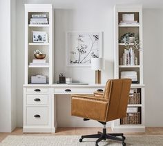 a brown leather chair sitting in front of a white desk with bookshelves and drawers