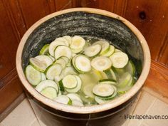 a bucket filled with lots of cucumbers sitting on top of a tiled floor