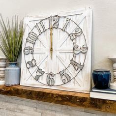 a clock sitting on top of a mantle next to vases and potted plants