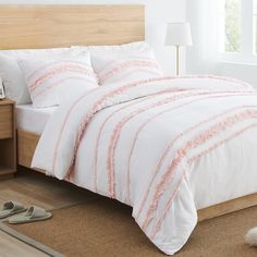 a bed with white and pink comforter in a bedroom next to a lamp on the floor