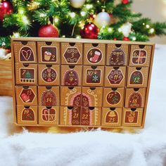 a close up of a wooden block with christmas decorations on it and a tree in the background