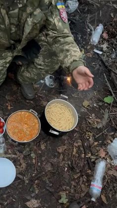 a man in camouflage sitting on the ground next to some food