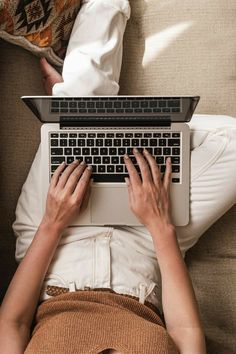 a person laying on a couch using a laptop computer with their hands resting on the keyboard