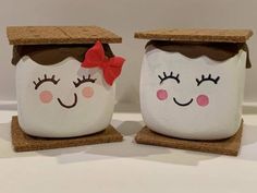 two ceramic jars with faces painted on them, one has a red bow and the other has a brown cap