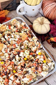 a tray filled with popcorn and candy corn on top of a table next to pumpkins