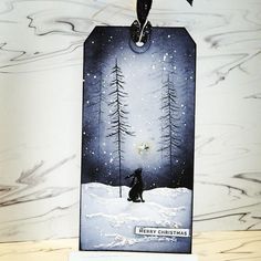 a christmas card with a bear in the snow and trees on it, hanging from a hook