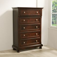 a wooden chest of drawers in a room with white walls and hardwood floors, along with a window