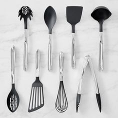 kitchen utensils lined up on a marble counter top with black and white spatulas