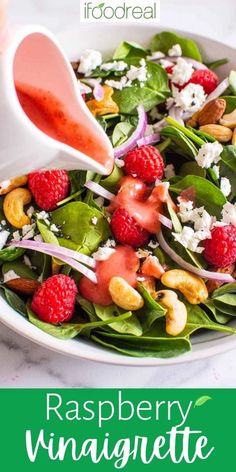 someone pouring dressing onto a salad with raspberries and spinach