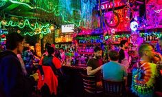 a group of people sitting at a bar with neon lights on the walls and ceiling