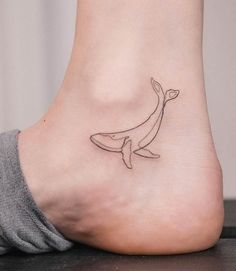 a small tattoo on the foot of a woman with a dolphin in it's mouth