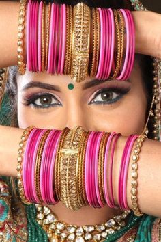 a woman with lots of bracelets on her face and hands in front of her face