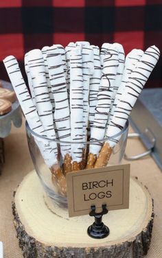 birch logs are arranged in a glass bowl on a wooden stand with a sign that says birch logs