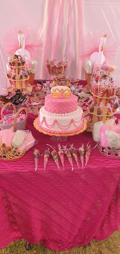 a table topped with a pink cake covered in frosting and lots of candies