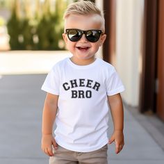 This is a perfect shirt for any Cheer Brother.  It would also make a perfect gift for a cheer Brother.   Uplift any child's wardrobe with a custom kid's t-shirt. The Bella Canvas short sleeve tee for toddlers is a 100% Airlume combed and ring-spun cotton jersey with a tear-away label for extra comfort. Choose your favorite color out of a big variety, and make unique staples that toddlers will happily wear every day.  .: 100% airlume combed and ring-spun cotton (fiber content varies for different colors) .: Extra light fabric (3.9 oz/yd² (132 g/m .: Tear-away label White Sports Fan Top With Text Print, White Tops With Text Print For Sports Fans, Team Spirit Short Sleeve School Top, School Team Spirit Short Sleeve Top, Short Sleeve Tops For School With Team Spirit Style, White Sports Fan Tops With Name Print, Short Sleeve Fan Apparel Tops For School, White Tops With Name Print For Fans, White Sports Fan Top With Name Print