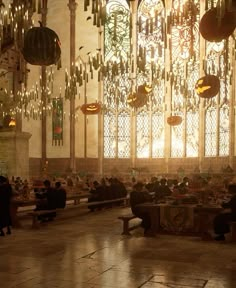 people sitting on benches in a large room with chandeliers hanging from the ceiling