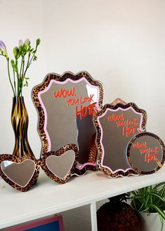 three decorative mirrors sitting on top of a white shelf next to a vase with flowers