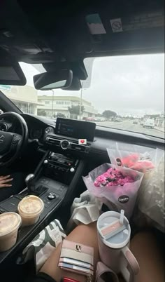 a woman sitting in the driver's seat of a car next to a cup of coffee