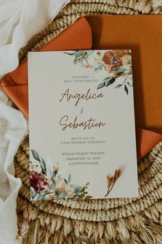 an orange and white wedding card sitting on top of a wicker basket