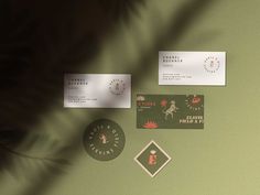 some business cards on a green surface with a plant in the middle and other items around them