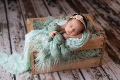 a baby is sleeping in a wooden crate with a stuffed animal on it's side