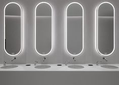 three sinks with mirrors on the wall above them in a public washroom or restroom