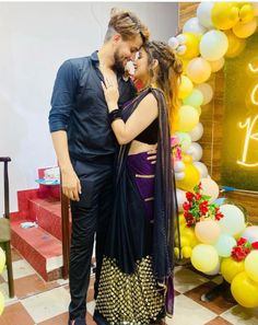 a man and woman standing next to each other in front of a cake arch with balloons