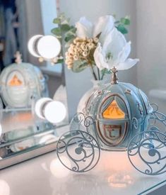 there is a small blue carriage on the table next to a mirror with flowers in it