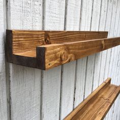 two wooden shelves on the side of a white painted building with wood trimmings