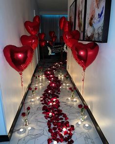 red heart shaped balloons are on the floor next to some candles and hearts in the hallway