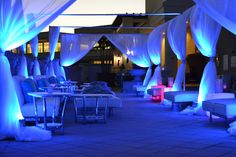 an outdoor seating area is lit up with blue lights and draping on the walls