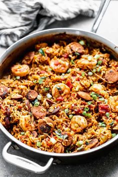 a large pan filled with rice and shrimp on top of a table next to a fork